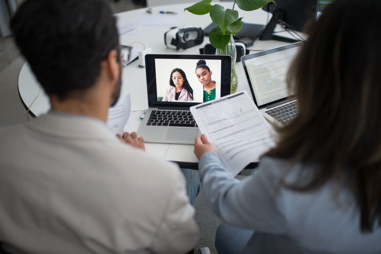 portfolio-04 Two professionals conduct a virtual job interview using laptops in a modern office.